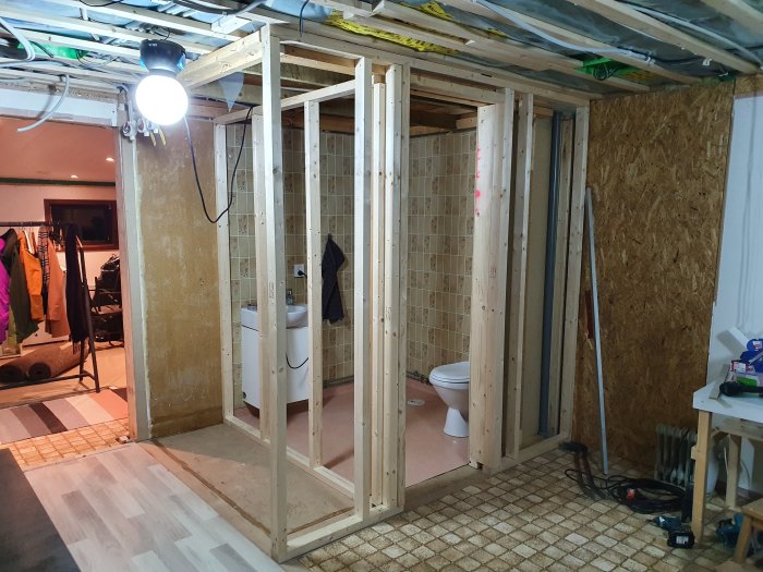 Renovering i process med uppställda reglar för vägg, en toalett och pågående elinstallationer.