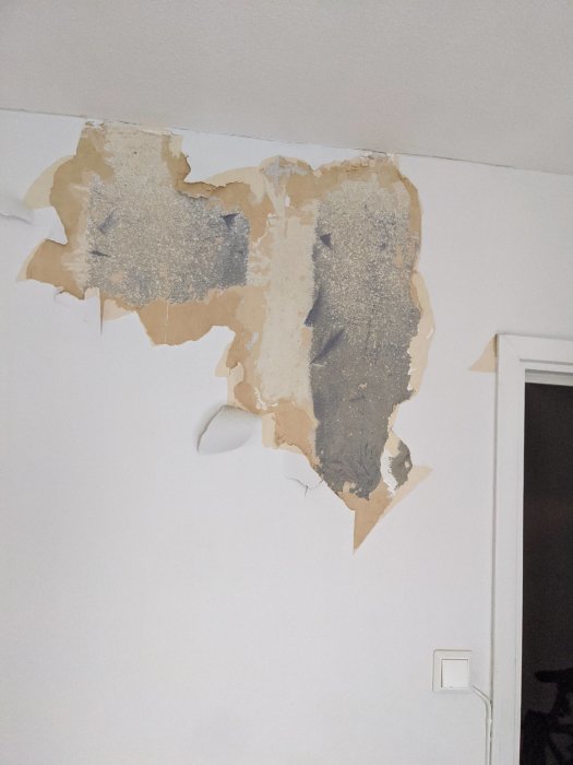 Innervägg där tapeter har rivits av och exponerat möjligt blåbetongmaterial.