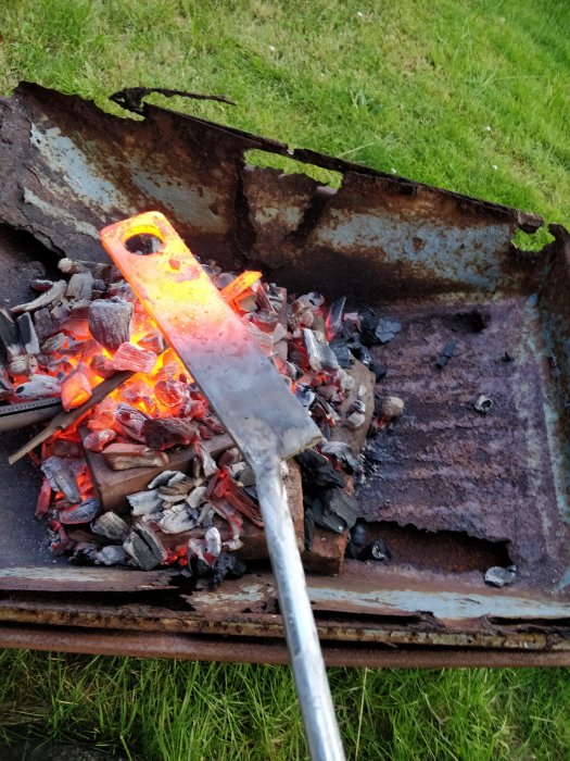 Metallstycke upphettas i en improviserad kolvärmare med glödande kol och eld.