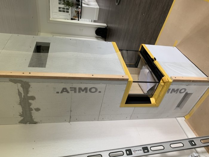 Inbyggnad under renovering med nylagt kakelfix och armeringsnät, ännu ofärdig med öppningar för rökrör.