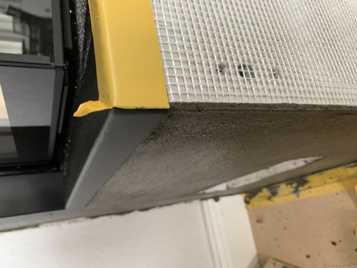 Nyligen putsad inbyggnad med armeringsnät och strukturerad yta vid kanten av en eldstad.