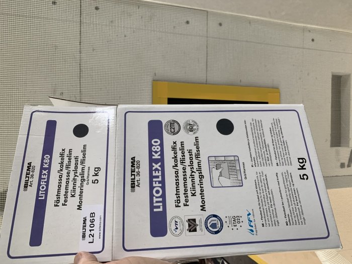 Två förpackningar av Biltemas kakelfix (LITOFLEX K80) på en byggarbetsplats.