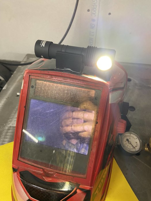 Svetshjälm med påmonterad lampa som belyser arbetsytan.