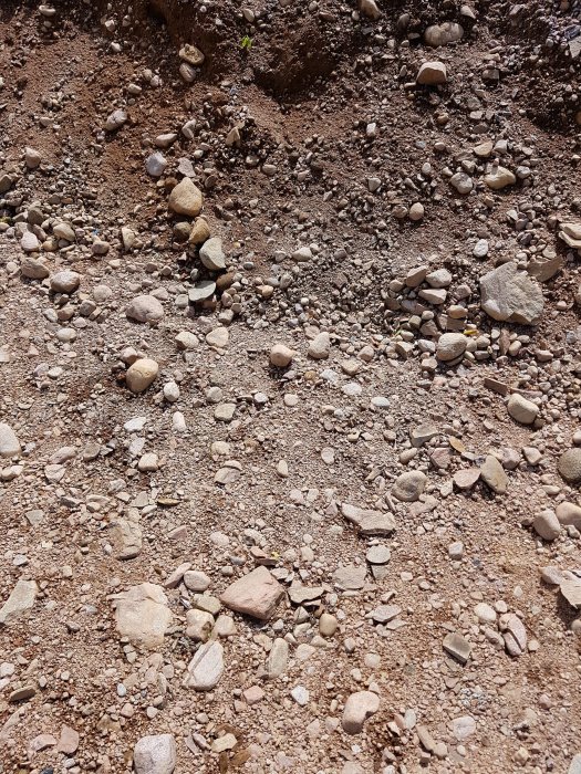 Mark med grus och stenar som är uppblandade i ett isälvs sediment, vilket visar svårigheten att borra.