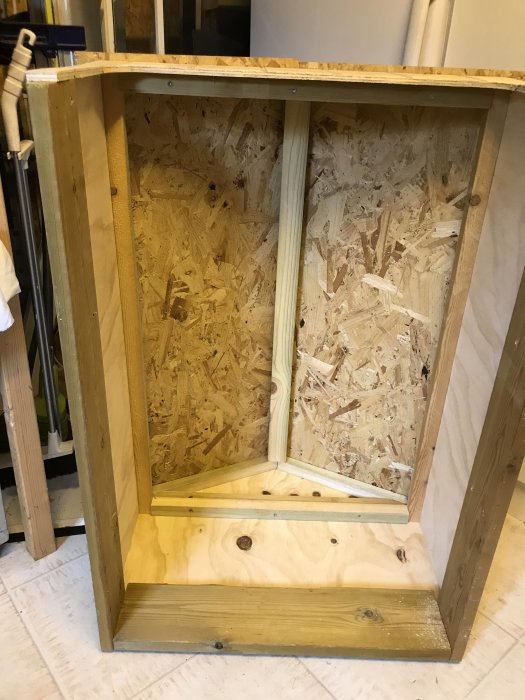 Hemmagjord träkonstruktion, möjligen ett djurhus, med OSB-tak och spårad plywood vägg.