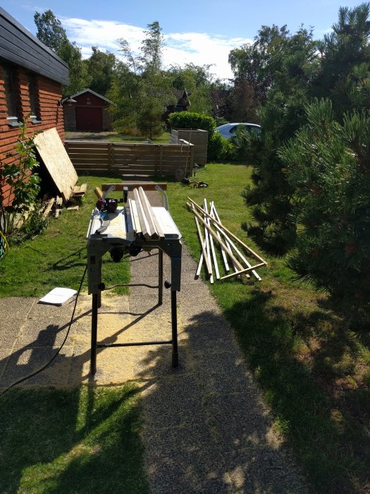 Bordssåg i trädgård med nysågade träplankor på marken.
