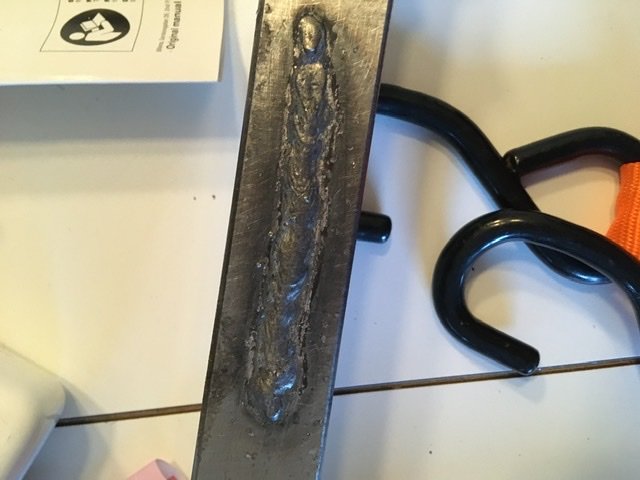 Ojämn och klumpig svetsfog på metallstång bredvid svetsmaskin, tecken på nybörjarsvetsning.
