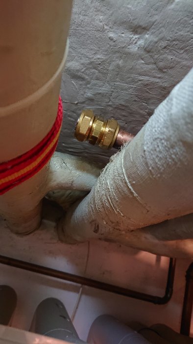 22mm pluggat kopparrör med klämringskoppling i en källare.