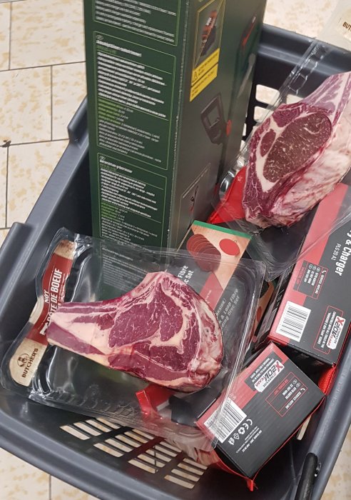 Inköpskorg med styckdetaljer av kött och verktygslådor, antyder leverans av mat och utrustning.