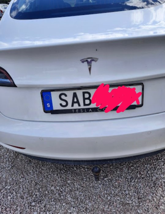 Vit Tesla bakifrån med felstavat SAAB-märke istället för riktig logotyp.