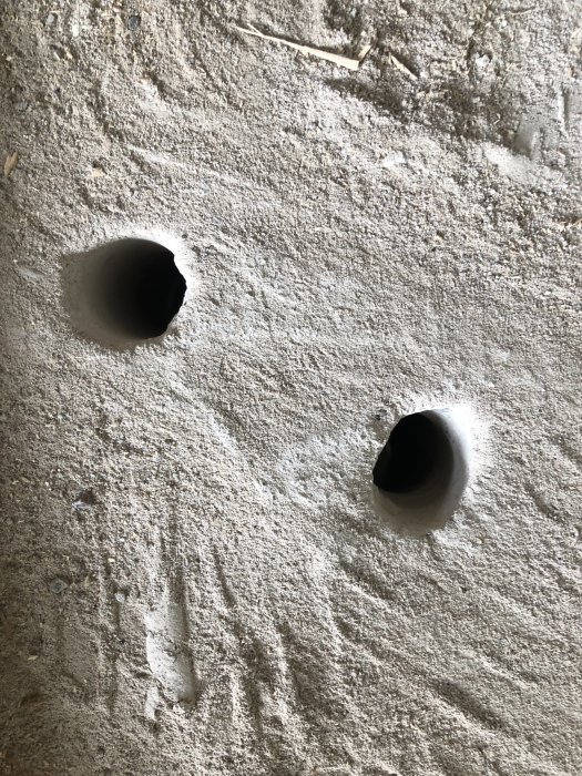 Två nya hål i ett betongbjälklag för LK-pex rörinstallation under renovering.