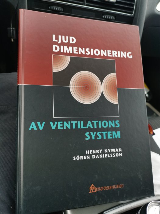 Bok om ljuddimensionering av ventilationssystem av Henry Nyman och Sören Danielsson i en bil.