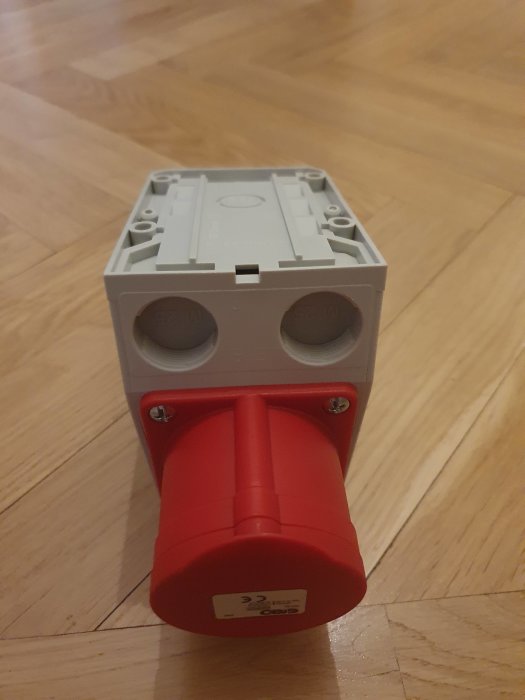 CEE 3N/16A+Shuko vägguttag för elinstallation, grå och röd, på trägolv.