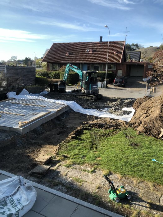 Nyutgjuten platta och markarbeten med grävmaskin vid en bostadsrenovering.