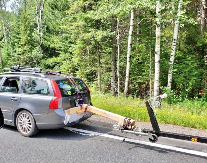 Bil med uppfinningsrik hemmagjord draganordning bestående av träplank och verktyg.