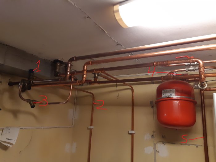 Översiktsbild av ett värmesystem inklusive rör, ventiler och ett expansionskärl markerade för identifikation.