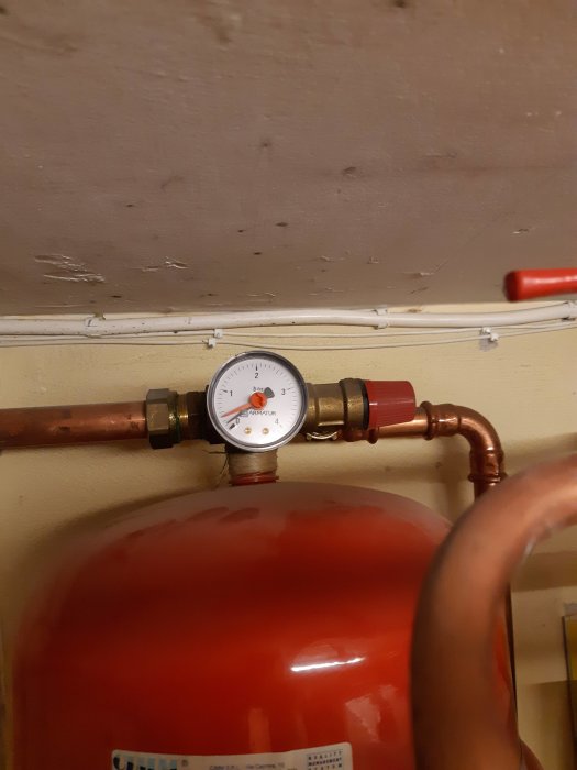 Expansionskärl i röd med tryckmätare och kopparledning ovanför.
