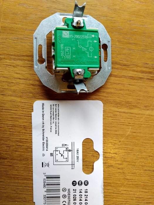 Baksida av en grön strömbrytare ovanpå dess förpackning med kopplingsschema.