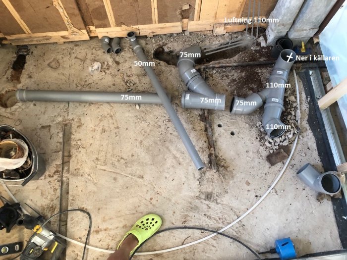 Renoveringsprojekt som visar avloppsrör i olika dimensioner installerade på ett betonggolv.