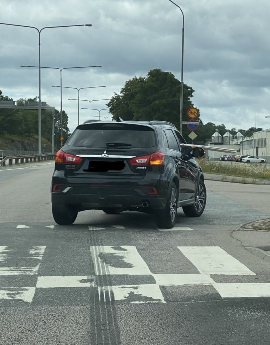 Svart SUV på en väg som ignorerar väjningsplikten vid ett övergångsställe.