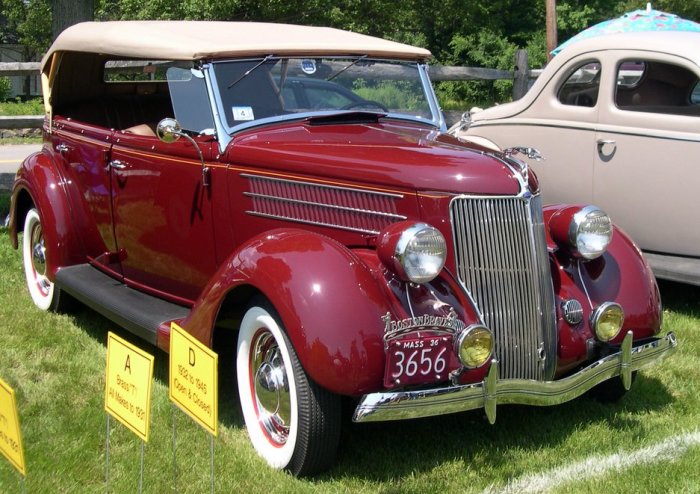 Röd Ford Model 48 cabriolet från 1935 med öppet sufflett och kromad stötfångare, visad på ett bilshow.