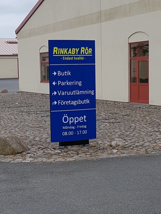 Skylt för Rinkaby Rör med pilar för Butik, Parkeringsplats, Varuutlämning och Företagsbutik med öppettider.