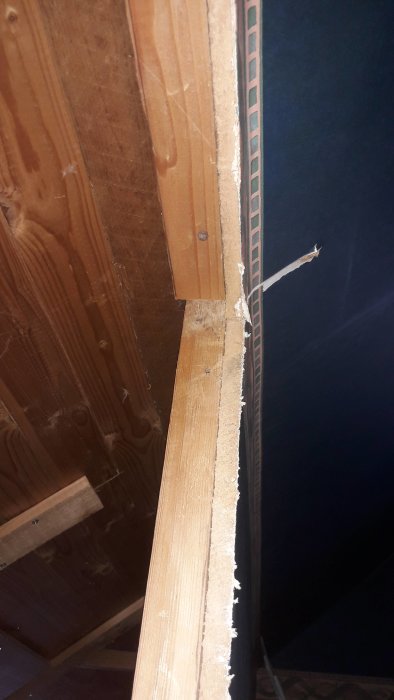 Inre hörn av en möjlig bärande trävägg med spontade plank och en synlig regel.