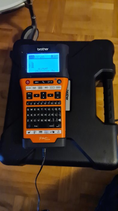 Brother märkmaskin P-touch E550W i en svart väska, med displayen påslagen visande texten "ALLMÄNT".