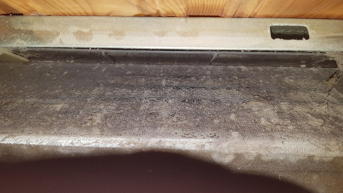 Ett dammigt och smutsigt utrymme under ett möbel efter 12 år utan städning.