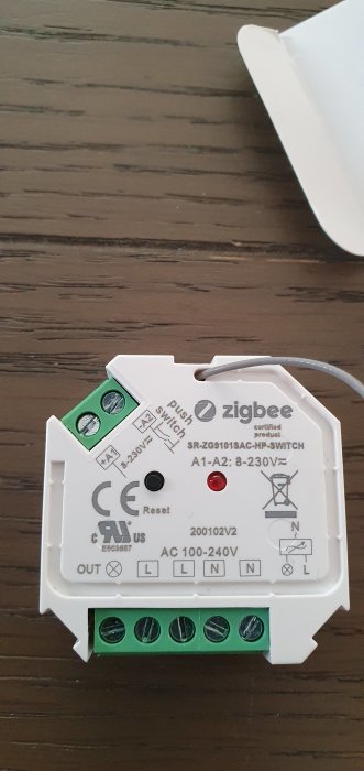 Zigbee in-wall switch på ett bord med synliga anslutningsterminaler och installationsinstruktioner.