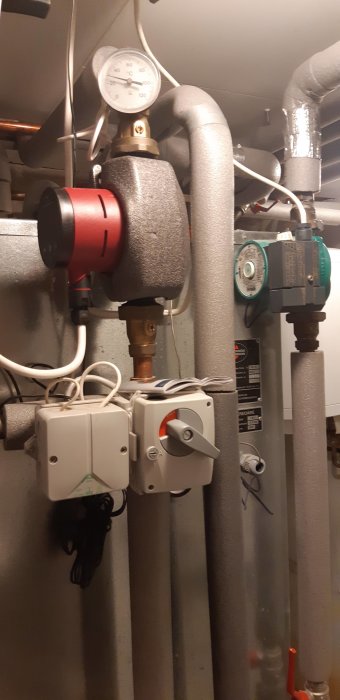 Bergvärmepumpskomponenter med mätare, cirkulationspump och expansionskärl i värmesystem.