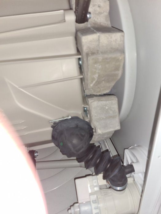 Bild på smulad betongklump under en Bosch tvättmaskin som visar möjligt tekniskt fel eller skada.