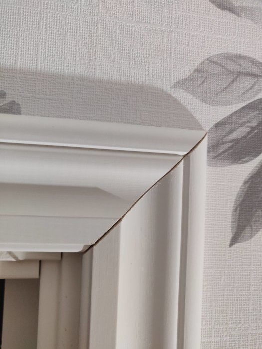 Glipa där två 45-graders kapade dörrfoder möts ovanför ett dörrfoder i ett hus.