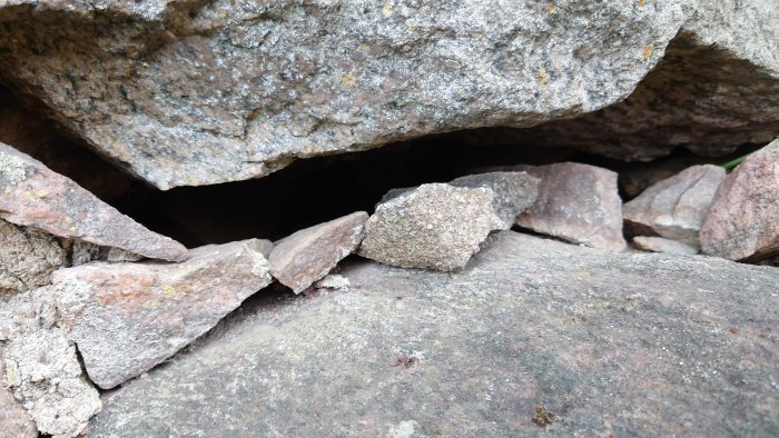 Grundmur med stora stenar och synliga håligheter där några mindre stenar har lossnat.