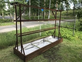 En nybyggd tomatlåda av trä med ställning för klättring utomhus.