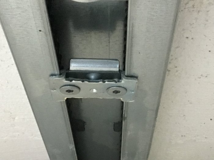Flyttbart stopp i metalldörrskena i taket med insexskruvar, kan justeras för portens stängning.