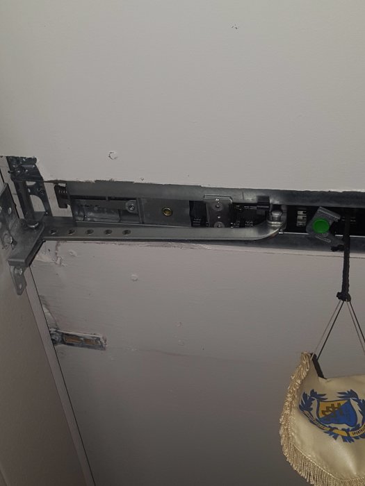 Bild på de övre skenorna där en garageportsrullare är monterad, med stoppklossar i fram- och bakkant.