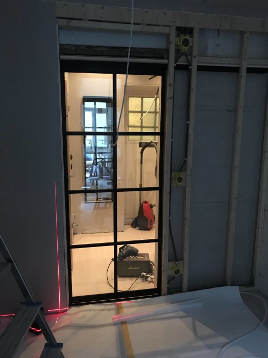 Nyinstallerad aluminiumdörr från Mirror Line i en byggmiljö med synliga verktyg och konstruktionsmaterial.