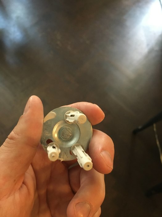 Hand håller en pluggad metallfäste med icke expanderade pluggar och synlig skruv längdskillnad.