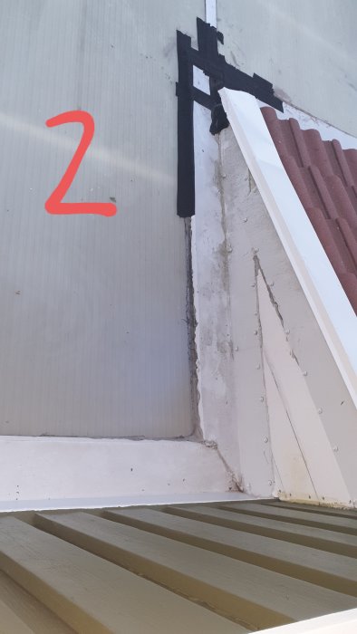 Del av ett hus med en läckande takdel där asfaltstejp använts som tätning mellan plåt och plast, behöver korrekt tätmetod.