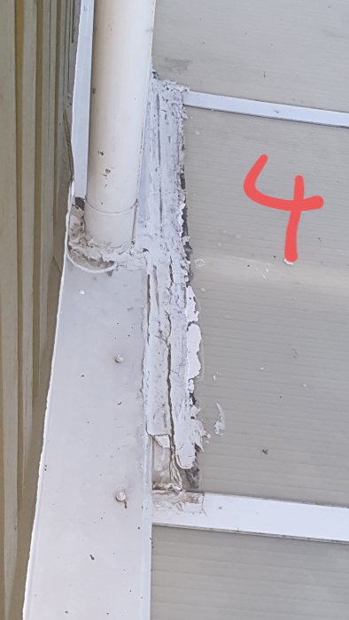 Skadat hörn av tak med misslyckad asfalttejpning och tecken på vattenläckage.