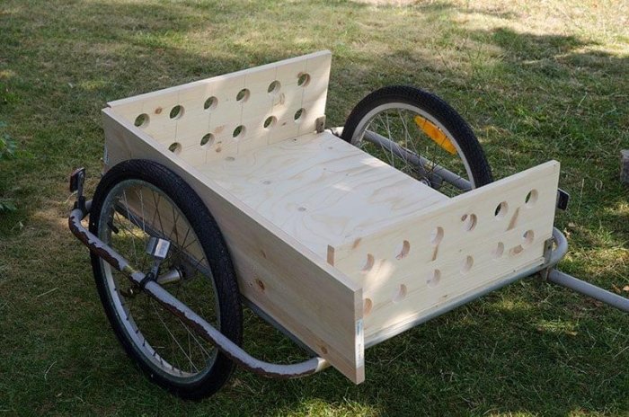 Ombyggd cykelvagn med plywoodbotten och limträsidor med hålmönster på gräsmatta.