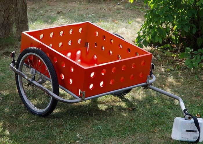 Ombyggd cykelvagn med röd plywood och limträsidor med hål, använd för transport.