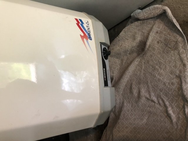 Värmepanna med synlig vattenläcka nära reglagen, täckt delvis av en grå handduk.
