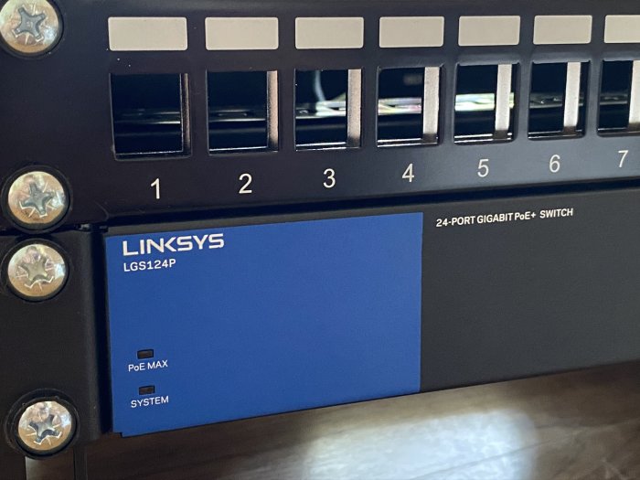 Linksys LGS124P 24-port Gigabit PoE+ switch monterad i nätverksskåp.