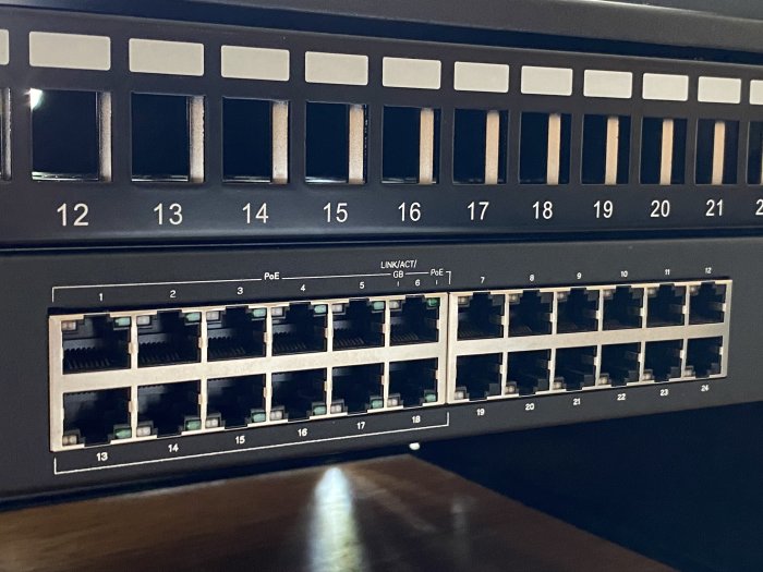 En nätverksswitch med 24 tomma portar och LED-indikatorer för PoE och länkaktivitet.