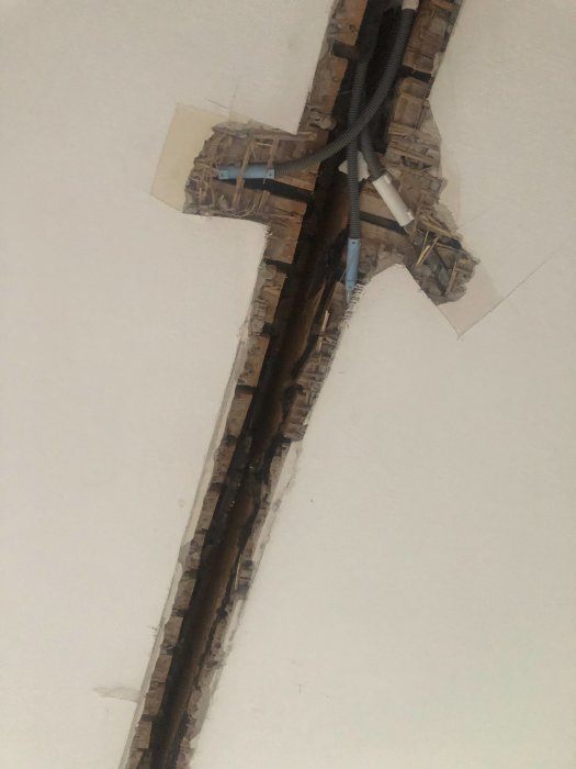 Rivet hål i taket uppvisar bar vävtapet, puts, och träbjälkar där en vägg tidigare funnits i en äldre lägenhet.