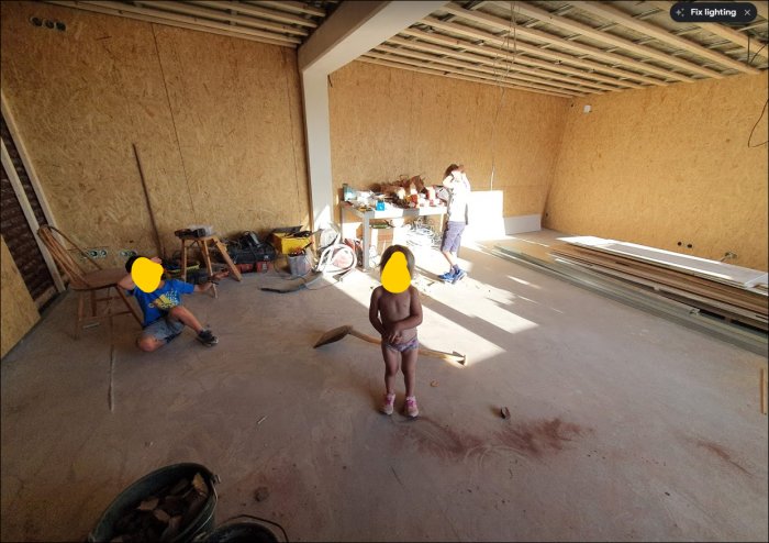 Under renovering, oisolerade OSB-väggar och ett barn och en vuxen arbetar i rummet.