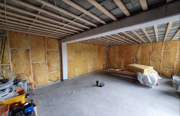 Renoveringsprojekt med isolering på väggar och uppreglade plåtprofiler i ett ofärdigt rum.