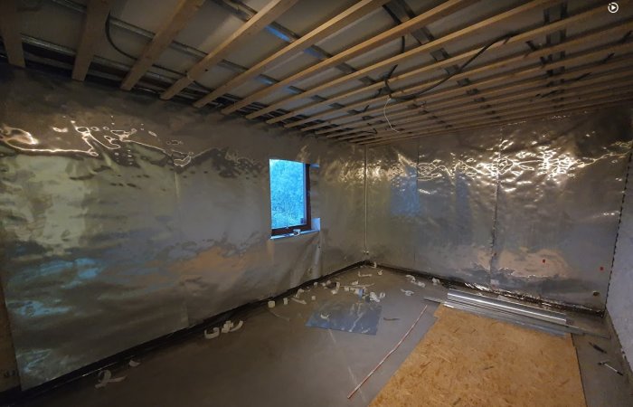 Renoverat rum med isolerade väggar och tak av lecablock, plåtprofiler och fibercementskivor, i ett skede före gipsning.